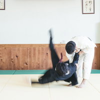 畳に叩きつけられるスーツ姿の会社員（一本背負い）の写真