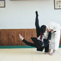 道場で繰り出す一本背負い、柔道着とスーツ姿の男性の写真