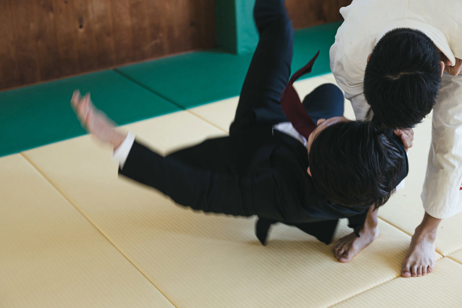 畳の上でスーツ姿の会社員が柔道で投げられて受け身を取っている［モデル：大川竜弥］