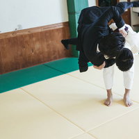 今日も柔道接待で一本背負い、道場でスーツ姿の男性が技を決めるの写真