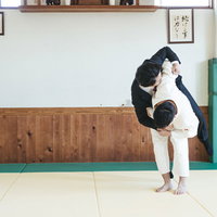 柔道場でスーツのサラリーマンを投げる柔道技の写真