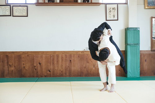 柔道場でスーツのサラリーマンを投げる柔道技
