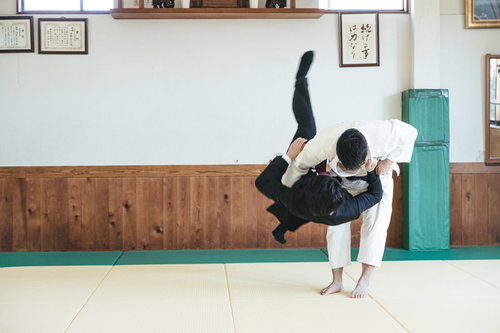 柔道場でサラリーマンを投げる白い柔道着の男性