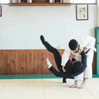 柔道場でスーツ姿の男性を投げる柔道の投げ技の写真