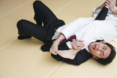 畳の上で腕ひしぎ十字固めを受ける会社員男性
