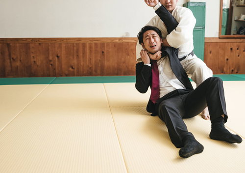 必死に片羽絞めから逃れようとするスーツ姿の会社員