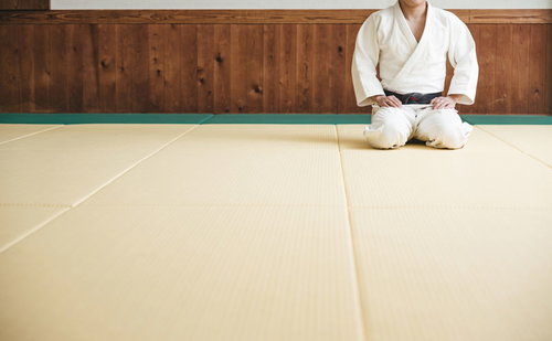 柔道場の畳で白い道着姿のまま静かに正座する選手