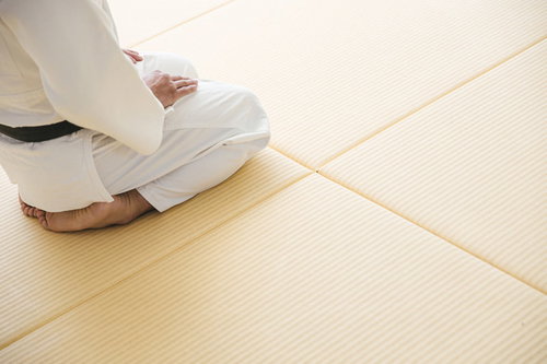 畳の上で正座する白い柔道着の男性柔道家