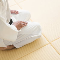 白い道着で畳の上に静かに正座する柔道家の姿勢と集中力の写真