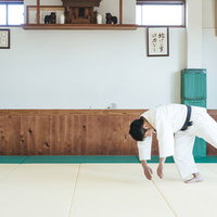 柔道の前回り受け身を実演する男性選手の稽古風景の写真