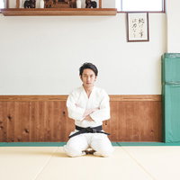 柔道場の畳で正座して腕を組む挑戦者の道着姿の写真