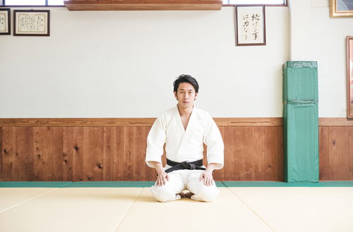 柔道着で畳の上に正座待機する男性