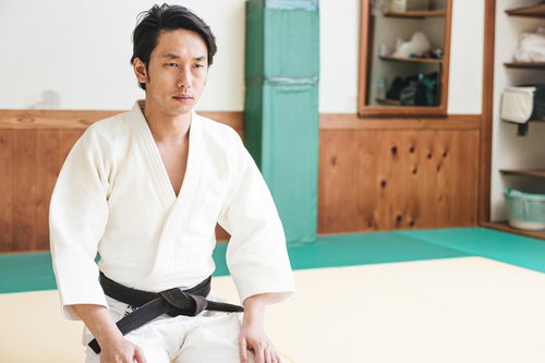正座して試合を見守る柔道の有段者（黒帯）