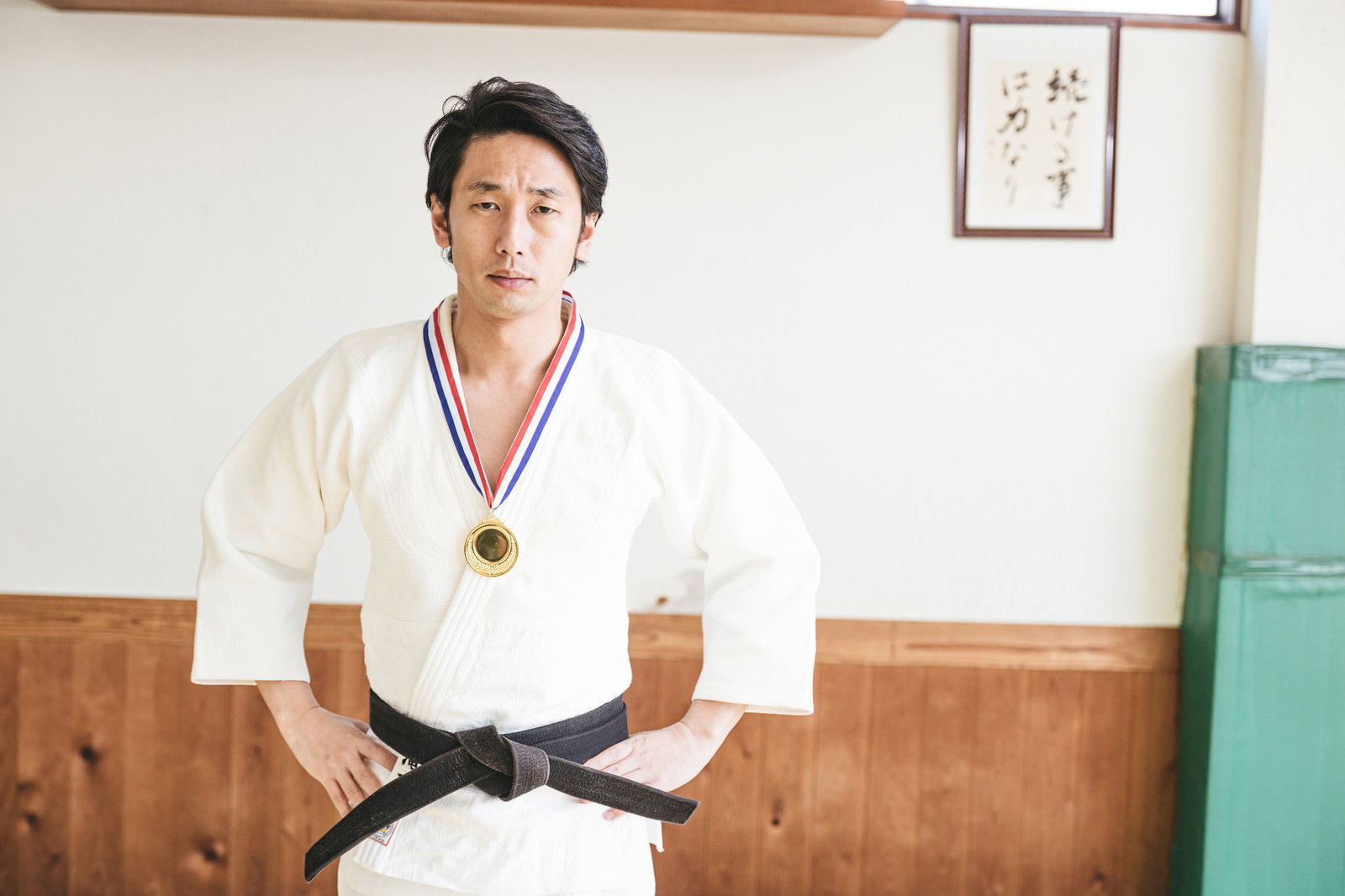 金メダルを首から下げて腕組みをする余裕の表情の柔道選手［モデル：大川竜弥］
