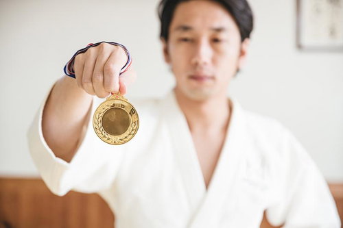 金メダルを掲げる柔道家の男性、受賞の喜びを表現