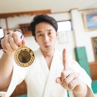 これもう1つください。金メダルを掲げるピースサインの柔道男性の写真