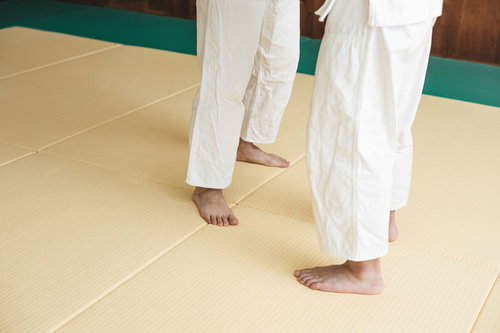 柔道の組手をしている選手たちの足元と道着、畳での稽古風景