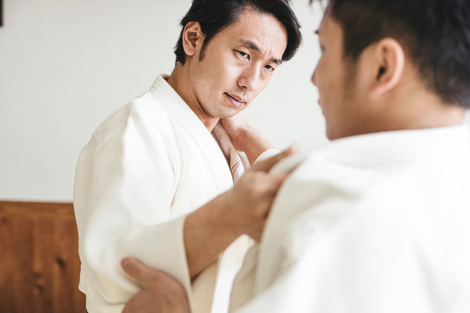 畳の上で白い道着を着た男性二人が組み手を取って稽古している様子［モデル：大川竜弥］