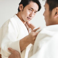 畳の上で組み合う柔道の両選手が力を合わせて稽古に励むの写真