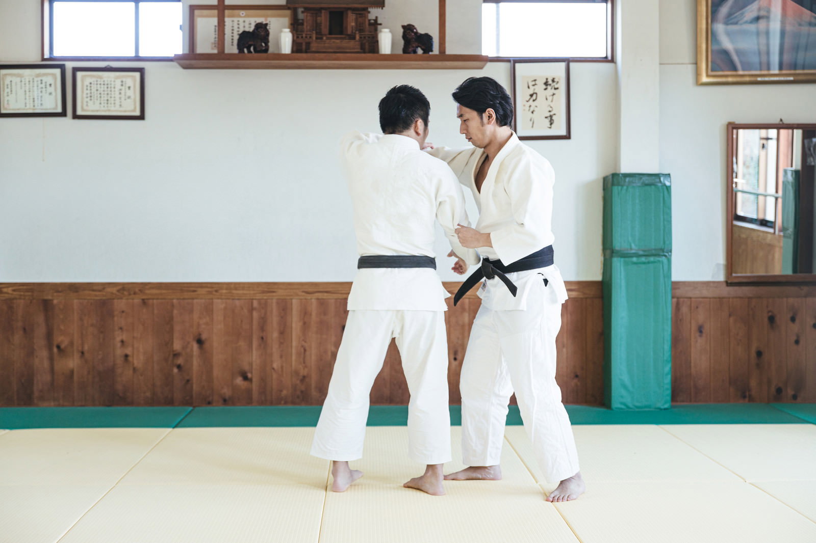 道場の畳で柔道着を着た男性が一本背負いの投げ技を決めている［モデル：大川竜弥］