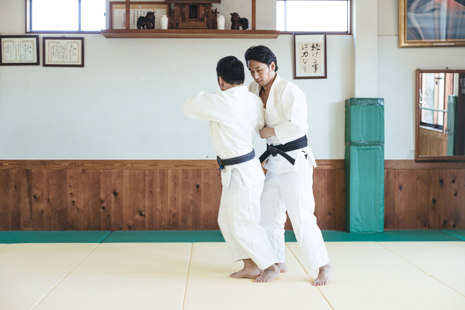 道場で白い道着を着た柔道選手が一本背負いの投げ技を決めている瞬間［モデル：大川竜弥］