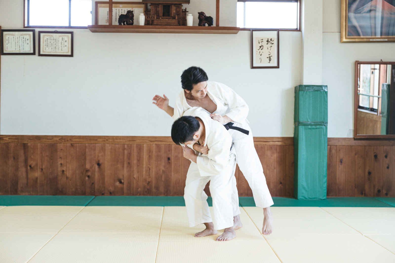 道場で白い道着を着た男性が柔道の一本背負いを決めている瞬間［モデル：大川竜弥］