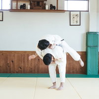 柔道の投げ技 一本背負いを道場で実演する男性の写真