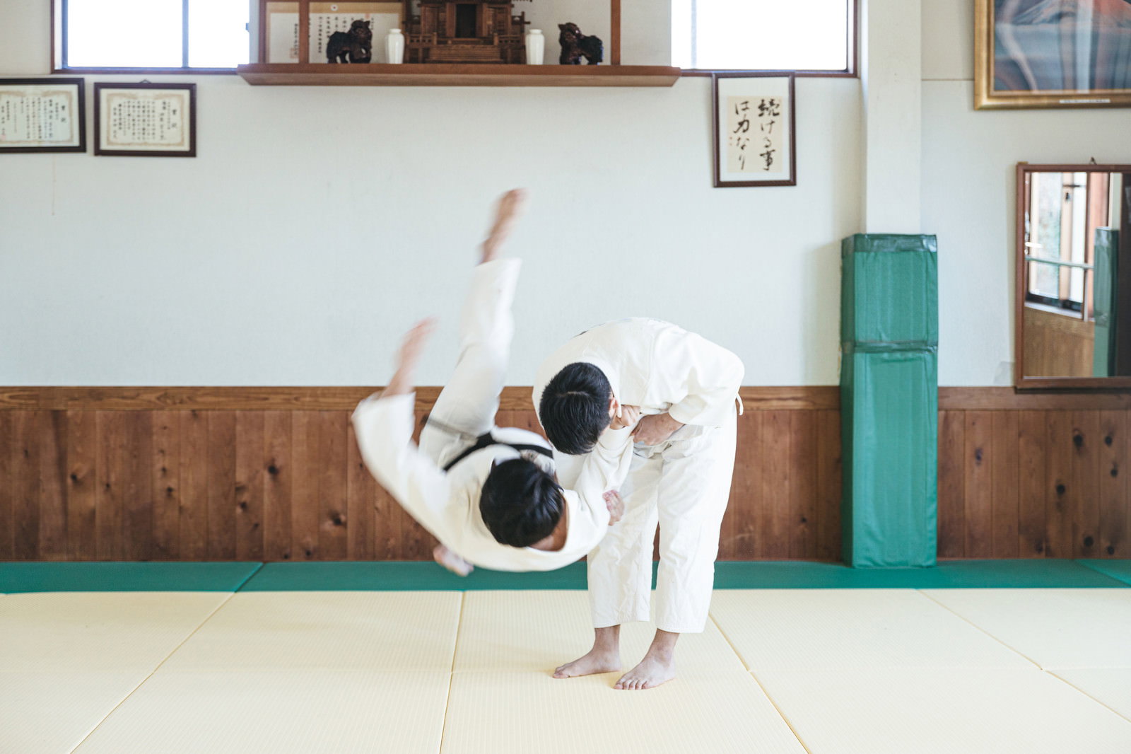 道場の畳の上で一本背負いの投げ技を決める柔道着姿の男性［モデル：大川竜弥］