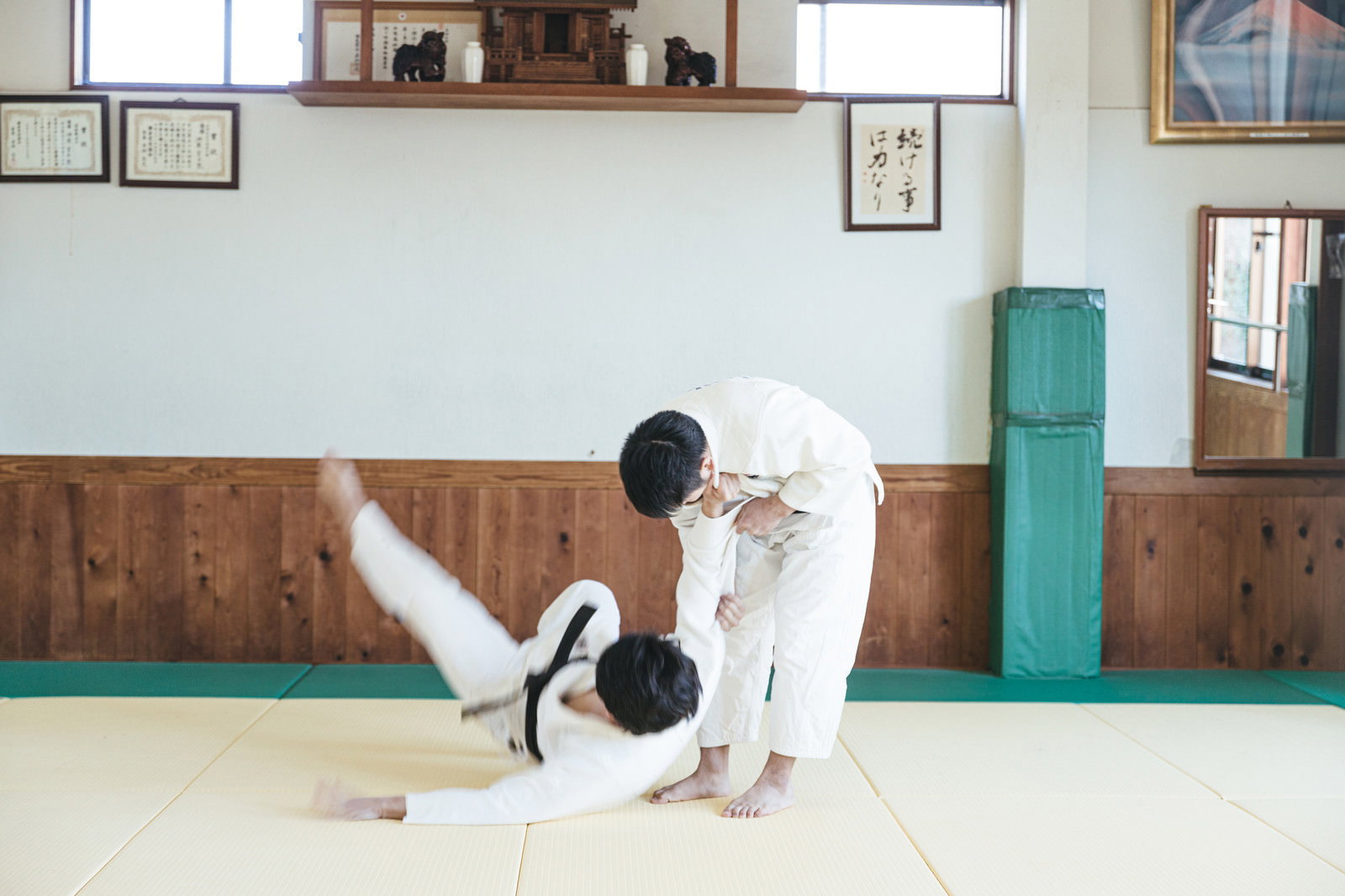 柔道場で一本背負いの投げ技を決める白い道着の男性選手［モデル：大川竜弥］