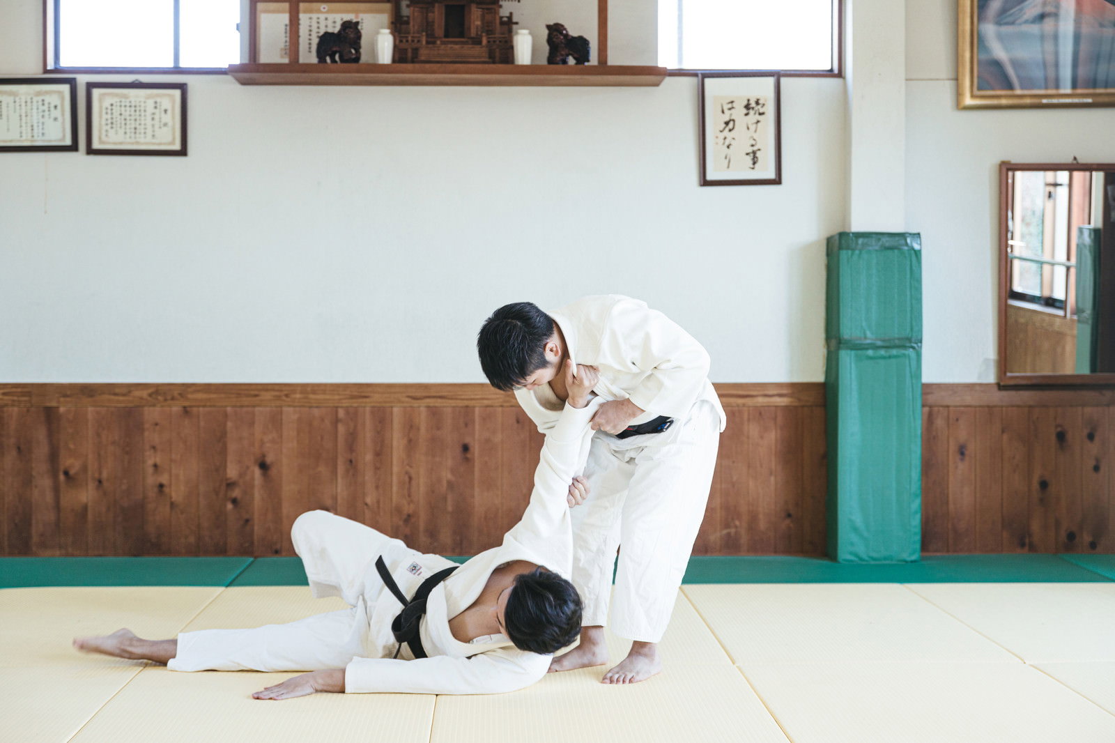 柔道場で白い道着を着た男性が一本背負いの投げ技を決める瞬間［モデル：大川竜弥］