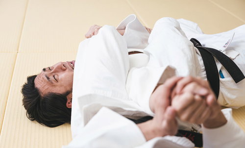 畳の上で腕ひしぎ十字固めが決まり苦しそうな柔道選手
