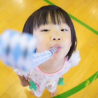ピロピロプーを吹く子ども、カラフルな背景で遊ぶ笑顔の写真