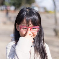 赤いフレームの眼鏡をかけた花粉症対策の少女の写真