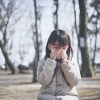 花粉症で目と鼻がつらい小学生の女の子のマスク姿の写真