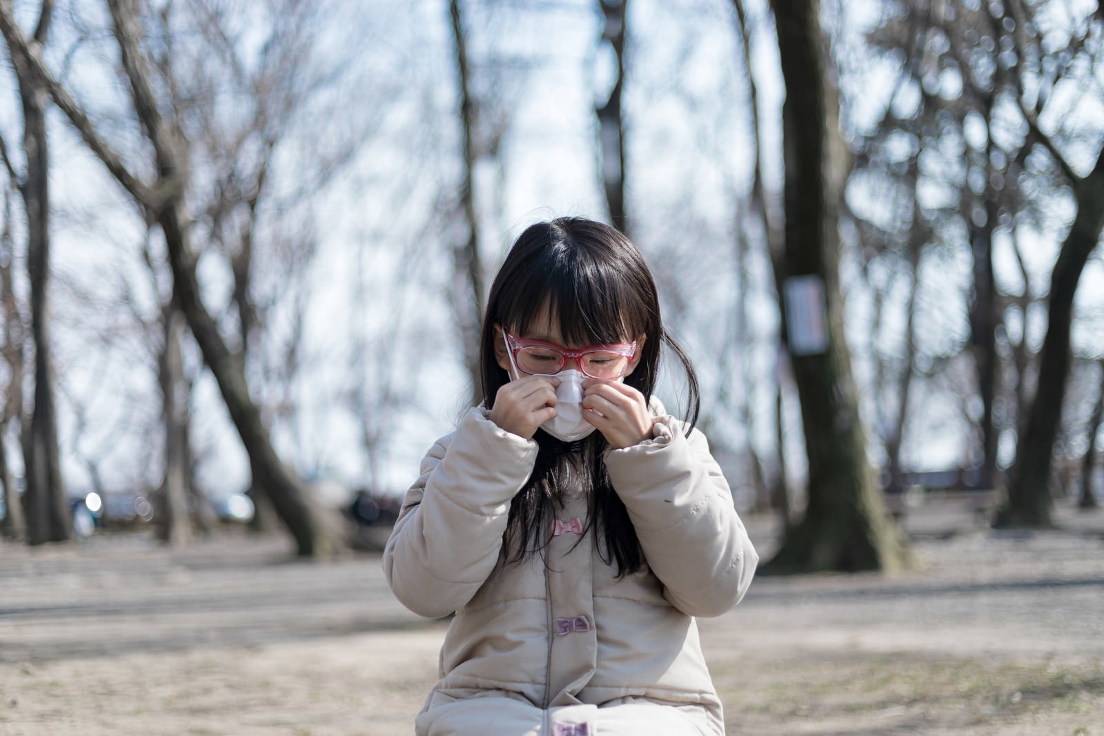 マスクを着用し手で顔を覆う眼鏡の女性［モデル：あんじゅ］