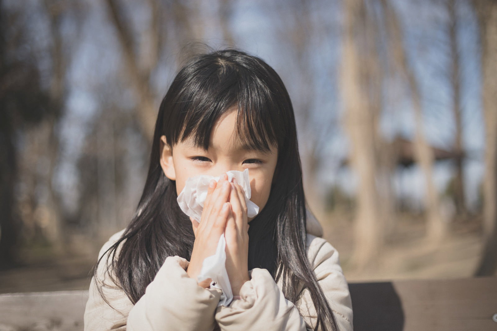 白いマスクをつけた女の子がティッシュで鼻をかんでいる様子［モデル：あんじゅ］