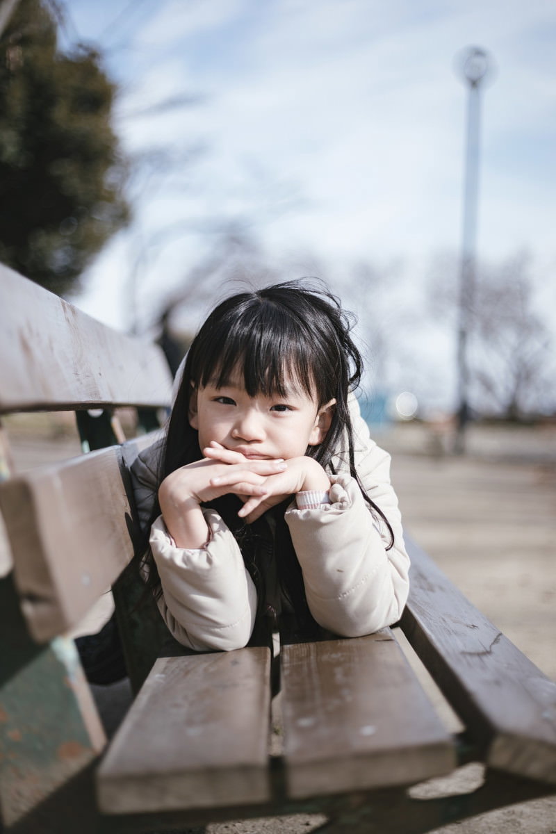 公園のベンチに座り、肘をついてほおづえをつく女の子［モデル：あんじゅ］