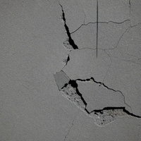 複数の亀裂が走る崩れた石膏ボードの壁のテクスチャーの写真