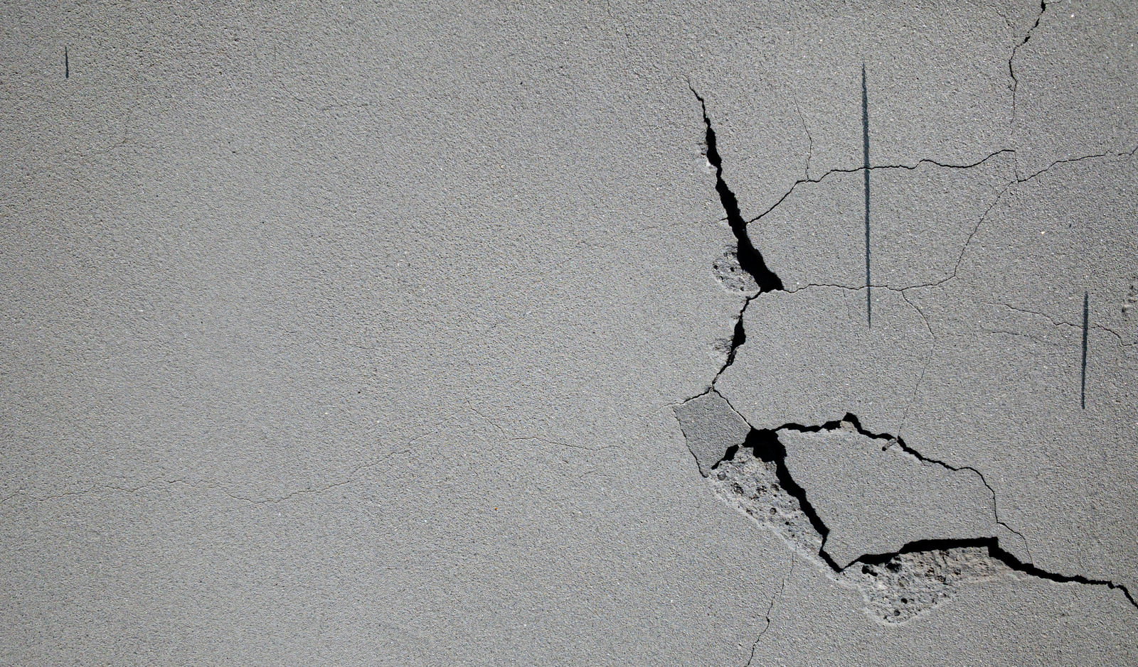 白い石膏ボードの壁に複数の亀裂やひび割れが入っている