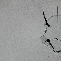 白い石膏ボードに走る亀裂とひび割れ、壁の経年劣化クラックの写真