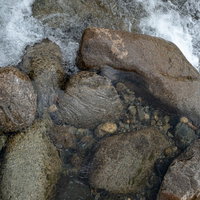 河原の岩や石の間を流れる透明な水の流れの写真