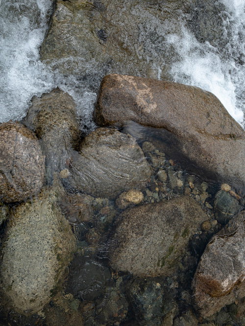 河原の岩や石の間を流れる透明な水の流れ