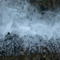 岩にぶつかり泡立つ勢いよい水の流れの写真