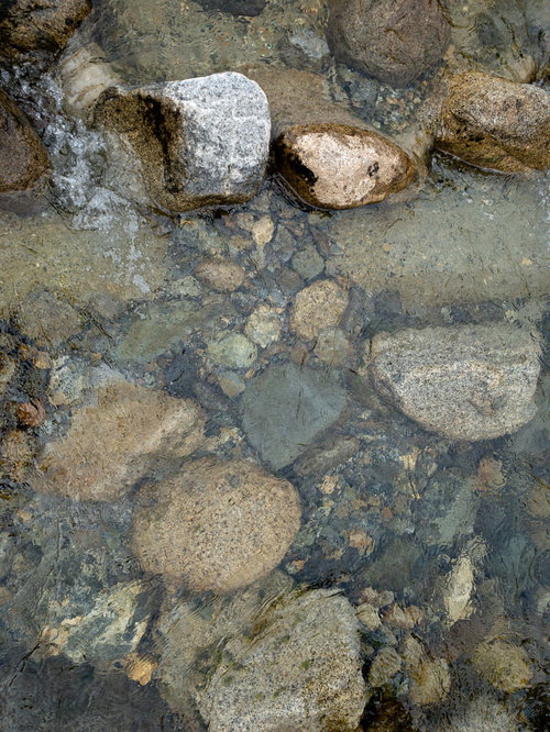 透明に澄んだ水の河原で見える川底の石と岩