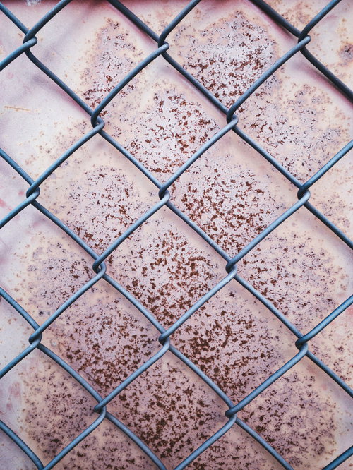 錆付いた金属板と黒い金網フェンスのテクスチャー