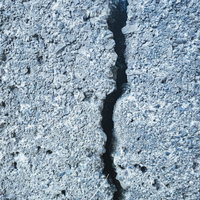 縦に走る亀裂のあるグレーのコンクリートブロック壁の写真