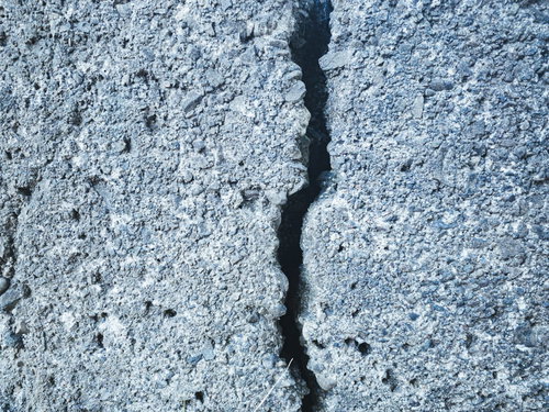 縦に走る亀裂のあるグレーのコンクリートブロック壁