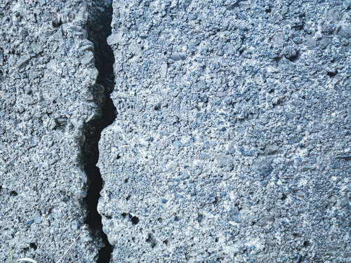 縦方向に走るクラックが入ったグレーのブロック壁