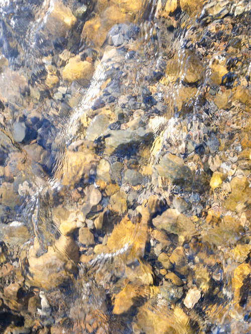 小川を流れる水面に映る川底の石や岩のテクスチャー