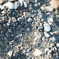大きめの石を退かした跡の凹みと砂利のテクスチャーの写真